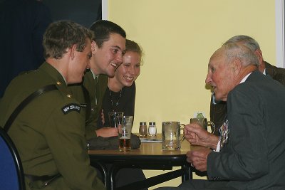 The young service men talk to the old veterans.. while enjoying a beer together.