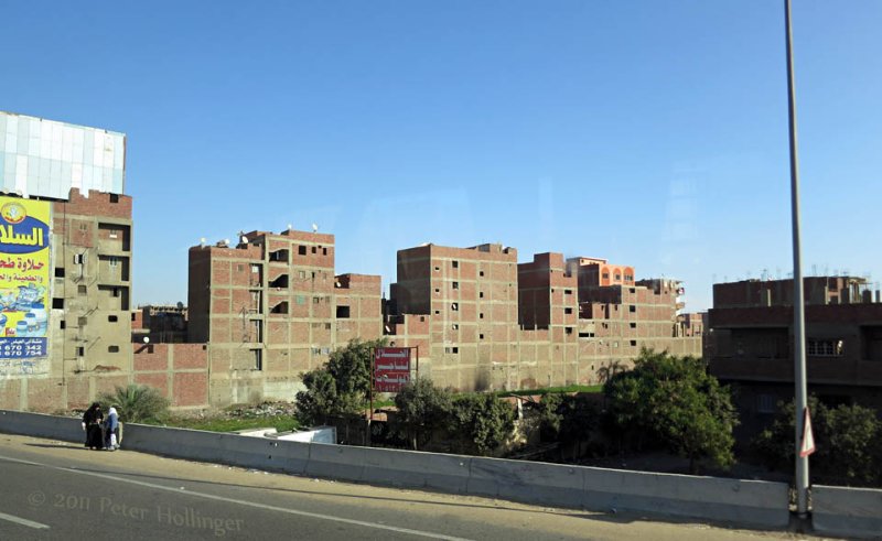 An unfinished apartment building bristles with satellite dishes