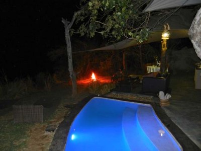 View of our pool at night, with dinner table in the background