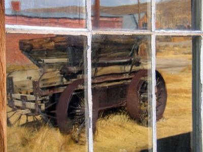 An old wagon mirrored in window at Bodie