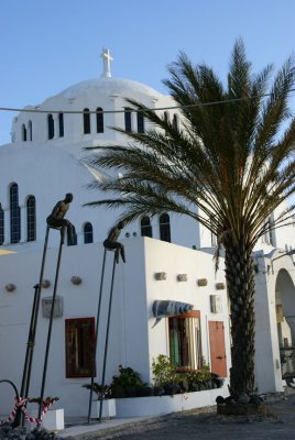 Modern art in front of boutique, with the Metropoli Orthodox Church in the background in Fira.