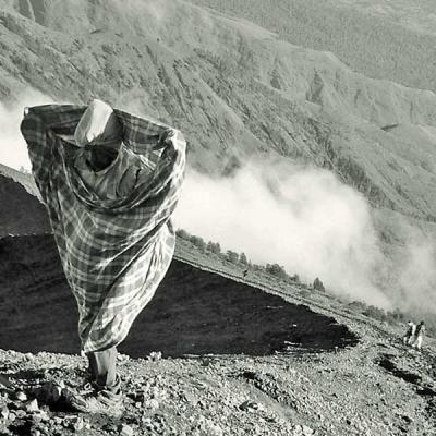 Indonesian porter wearing only a sarong as insulation, making his way up the summit of Mount Rinjani, Lombok, Indonesia