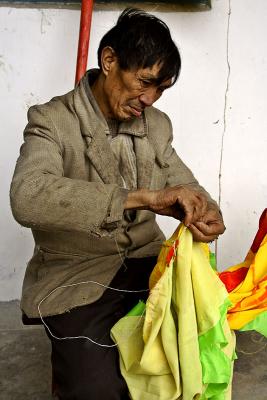Sewing on the dragon tail for new years. Pan Zhai Village, Guizhou, China