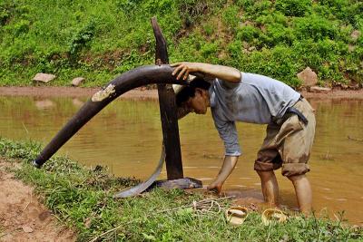 Washing his plow after a day of work. Ping Shan Po, Wuling Mts. Hunan, China