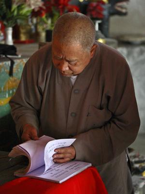 Buddhist monk using a reference book for fortunes.