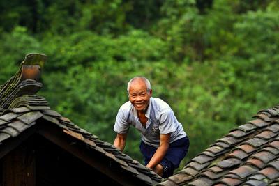 Hmong elder working on his roof.