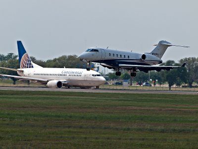 A Bombardier DD-100 landing in front of a continental airliner waiting for clearance. 