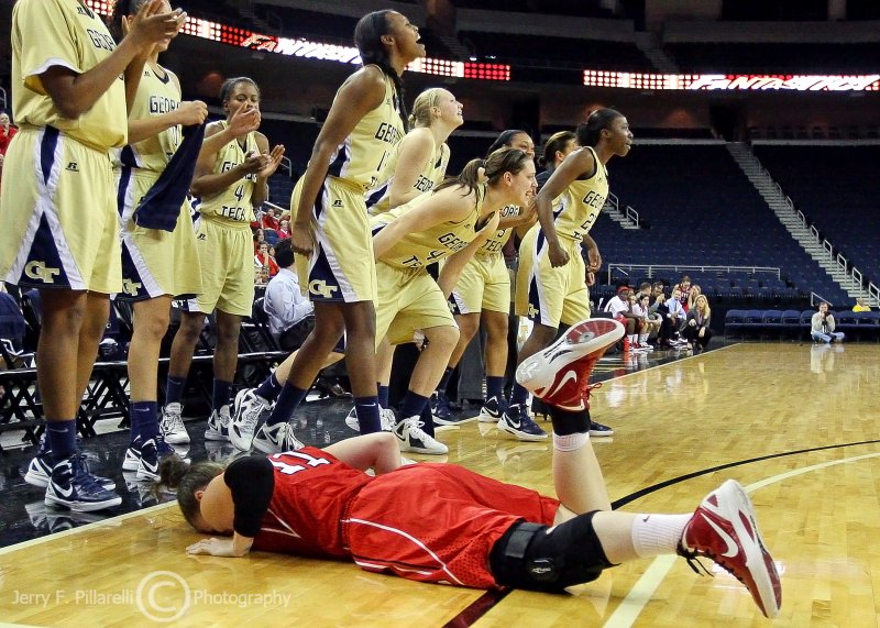 Georgia Tech Bench cheers on a teammate while NC State G Tasler sprawls nearby after an injury