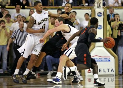 Yellow Jackets G Lance Storrs and C Daniel Miller are screened as Hurricanes G Malcolm Grant drives the lane