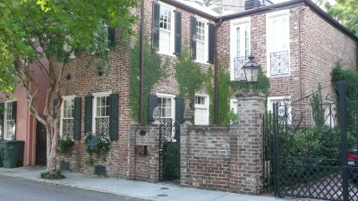 Stone pineapples (the symbol of welcome in Charleston) and creeping fig on an old brick house.