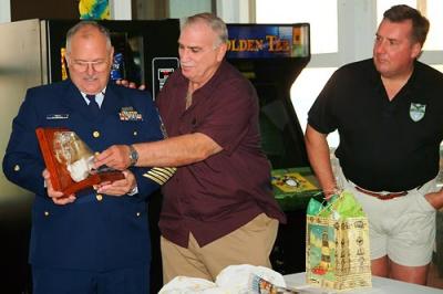 BMCM Paul DeBold opening gifts at his retirement ceremony with DC1 Dave Shiffman assisting and CDR Fred Remen observing