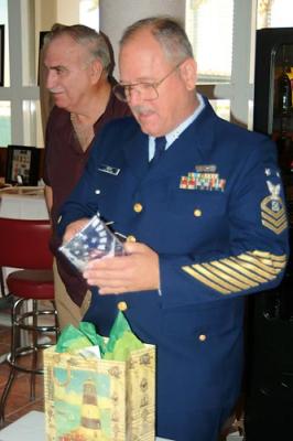 BMCM Paul DeBold opening gifts at his retirement ceremony, DC1 Dave Shiffman in back