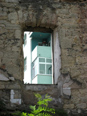 a rebuilt apartment building seen through the ruins of another apartment