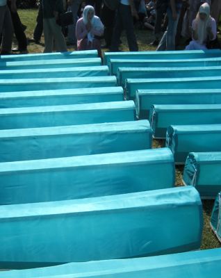 women praying over the caskets of family