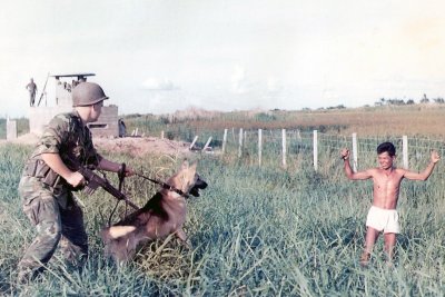 Kidd & King staging a photo with an ARVN soldier posing as a Viet Cong sapper looking towards perimeter of the base.