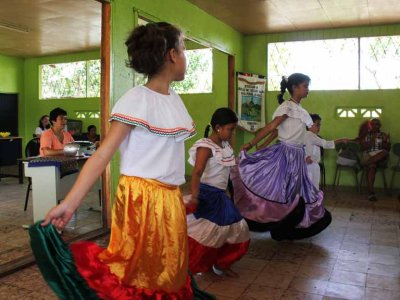 Students dancing at a small, rural school. The teacher (orange blouse) is playing music on a boombox.