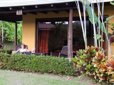 Judy outside our unit (room) at Hotel Arenal Manoa. The nearby active Arenal Volcano can be seen as a reflection in the window.