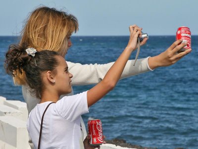 Two Girls, two cans of  Coca-Cola and a photocamera.