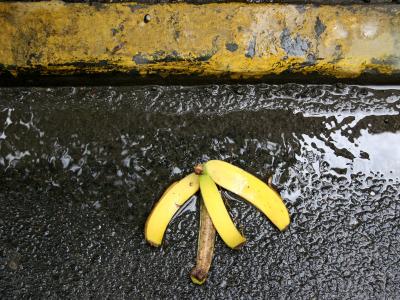 Banana Peeling at a Sidewalk Curb on a Rainy Day