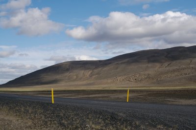 In the highlands, in snow and fog, yellow poles mark the road.
