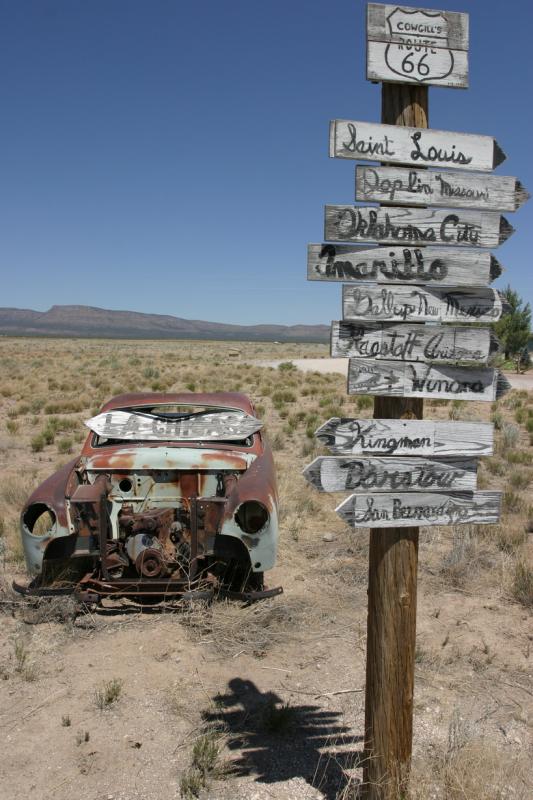 sign post and rusted out car