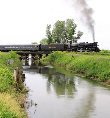 NKP 765 charges across a small creek near La Crosse on a cloudy Sunday Morning
