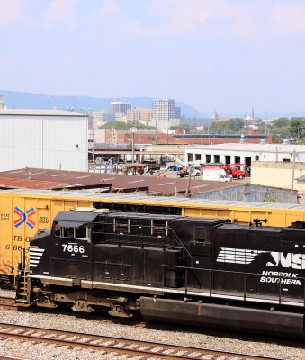 NS 7666 departs Debutts yard, with the city skyline as a backdrop 
