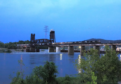 A Southbound grain train crosses over the TN river at dusk. 