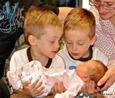 2 big brothers holding baby sister first time