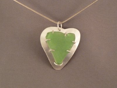 Heart-shaped beach glass held to the sterling back plate with sterling prongs.