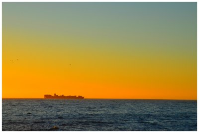 Container ship going around the southern tip of Africa magnified in the evening sunset
