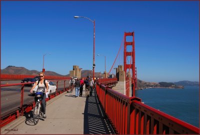 Bikers , walkers and traffic on the Golden Gate  Bridge and river traffic  below.