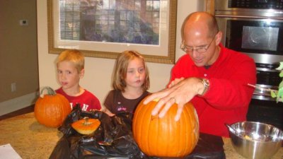 daddy carves the pumpkin, with e's illustration drawn on it