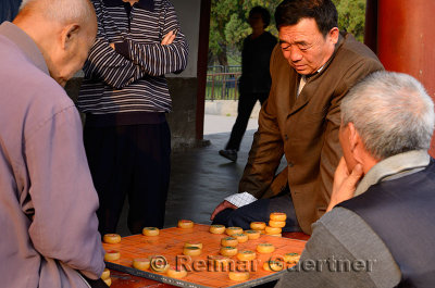Group of men watching pair play Chinese Chess or Xiangqi in Beijing China