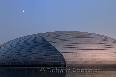 Abstract architecture of the National Centre for the Performing Arts with moon at dusk in Beijing