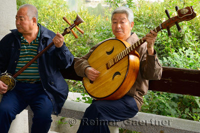 Two men playing a Chinese banjo and Ruan in an orchestra outdoors at Zizhuyuan Purple Bamboo Park in Beijing