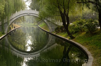 Men fishing in Changhe river with stone bridge in Zizhuyuan Purple Bamboo Park Beijing