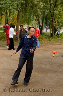 Man spinning a Chinese Yo Yo in Zizhuyuan Purple Bamboo Park in Beijing China