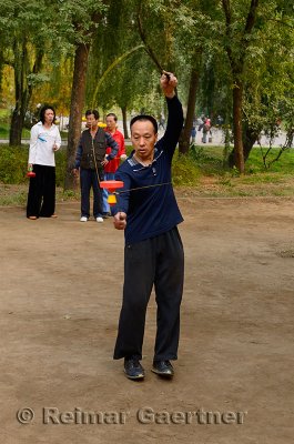 Skilled man doing tricks with Chinese Yo Yo in Zizhuyuan Purple Bamboo Park in Beijing China