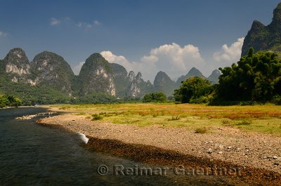 Pebble shore of the Lijiang River China with pointed Karst cones and peaks