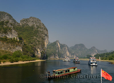 Cruise ships and rusted barge on the Li River Guangxi China with karst dome mountains