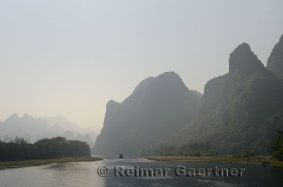 Cruise ship on the hazy Li River in China among the karst limestone peaks of Guangxi