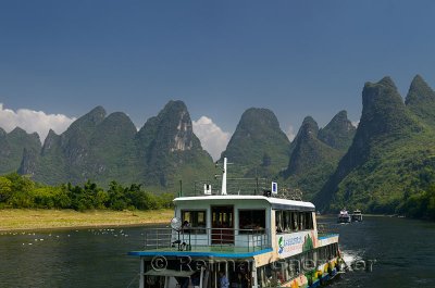 Chinese tour boats cruising the Li river Guangxi China with tall karst peaks