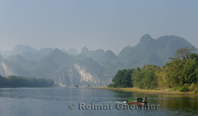 Old barge and cruise boats on the Li River Guangxi China with karst dome mountains