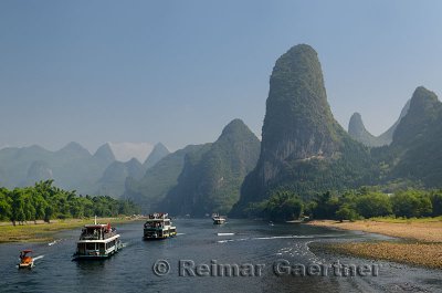 Tour boats traveling down the Li river Guangxi China with tall karst mountain cones