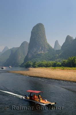 Tour boat raft traveling down the Li river Guangxi China with tall karst mountain cones