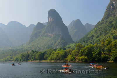 Tour boat rafts on the Li river Guangxi China with pointy karst mountain peaks in the haze