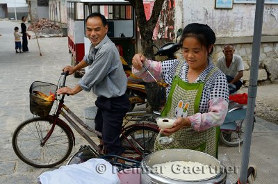 Street vendor ladelling syrup onto fresh curd Douhua in Fuli China