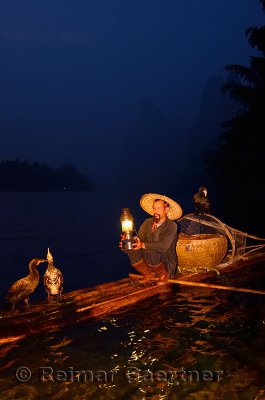 Early morning Cormorant fisherman with lamp on bamboo raft on Li river near Xingping China