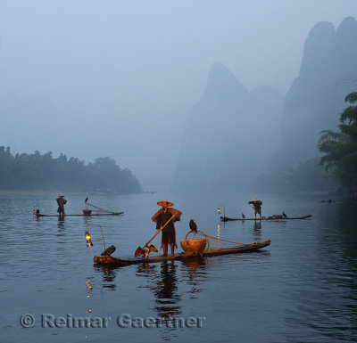 Cormorant fishermen on the Li river at dawn with Karst mountain peaks in mist near Xingping China